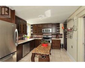 A kitchen with a table in the middle and a refrigerator on the left.
