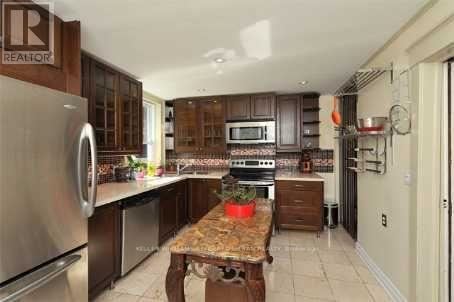 A kitchen with a table in the middle and a refrigerator on the left.