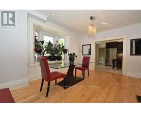 A dining room with a glass table and red chairs.