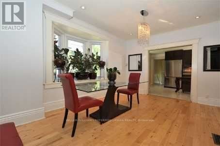 A dining room with a glass table and red chairs.