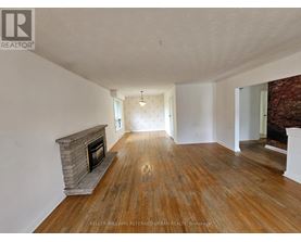 A spacious room with a fireplace and wooden flooring.