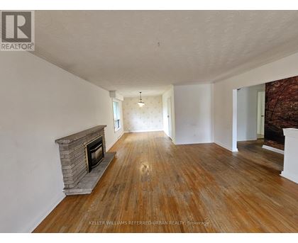 A spacious room with a fireplace and wooden flooring.