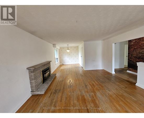 A spacious room with a fireplace and wooden flooring.