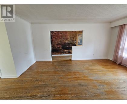 A room with a wood floor and a painting of a forest scene on the wall.