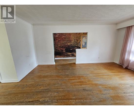 A room with a wood floor and a painting of a forest scene on the wall.