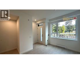 A room with a door and a window with a view of trees and a fence outside.