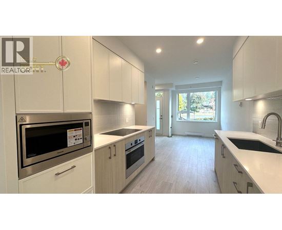 A modern kitchen with white cabinets and stainless steel appliances.