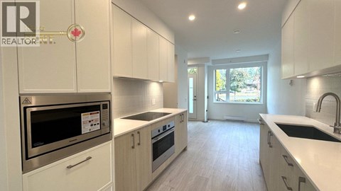 A modern kitchen with white cabinets and stainless steel appliances.