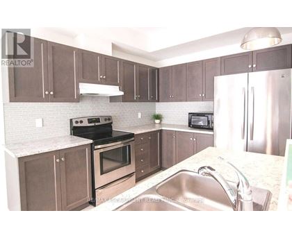 A kitchen with brown cabinets and a stainless steel refrigerator.