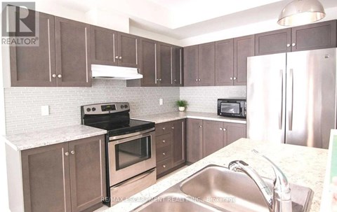 A kitchen with brown cabinets and a stainless steel refrigerator.