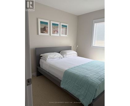 A bedroom with a bed, pillows, and pictures on the wall.