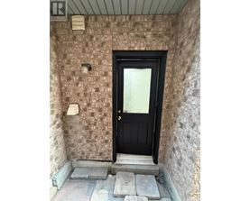 A black door is at the end of a stone wall.