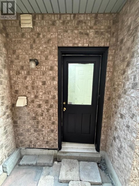 A black door is at the end of a stone wall.