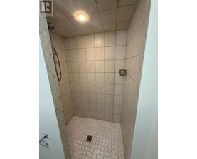 A shower with a white tile floor and walls.