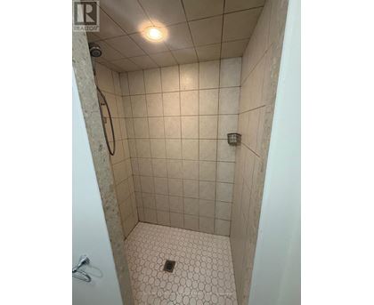 A shower with a white tile floor and walls.
