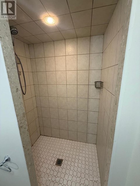 A shower with a white tile floor and walls.