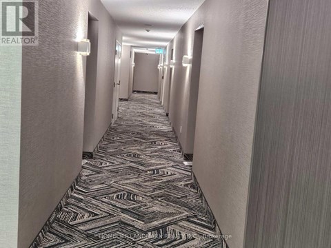 A long hallway with a carpeted floor and doors on both sides.