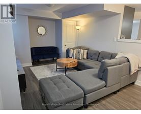 A grey couch with a round wooden table in front of it.
