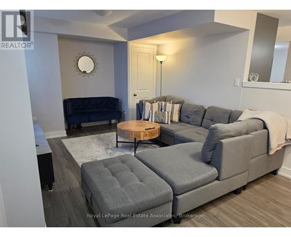 A grey couch with a round wooden table in front of it.