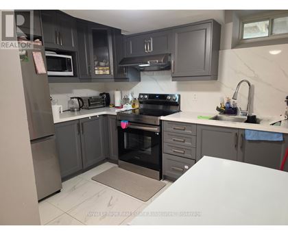 A kitchen with a refrigerator, oven, and sink.