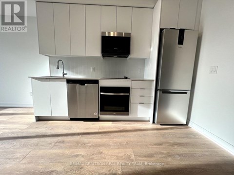 A kitchen with white cabinets and appliances in a room with a tiled floor.