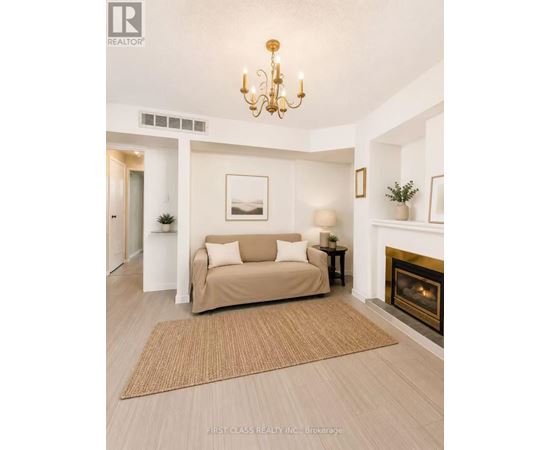 A living room with a beige couch, a fireplace, and a chandelier.