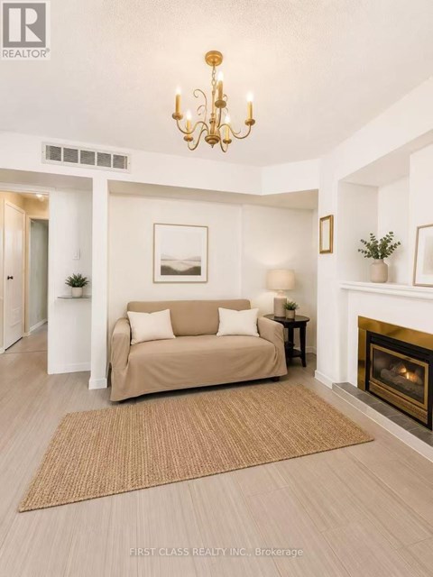 A living room with a beige couch, a fireplace, and a chandelier.
