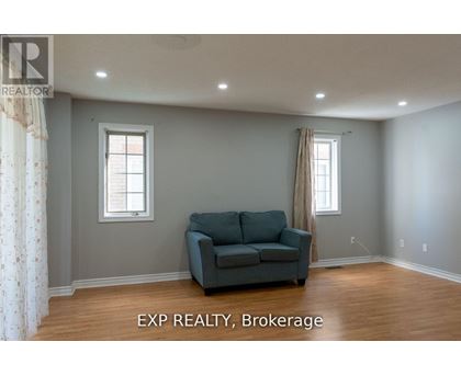 A living room with a grey couch and two windows.