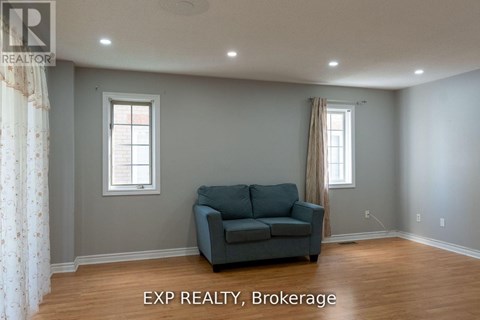 A living room with a grey couch and two windows.