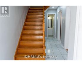 A wooden staircase leads to a hallway with a mirror on the wall.