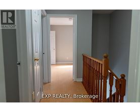 A hallway with a wooden staircase and a door on the left.