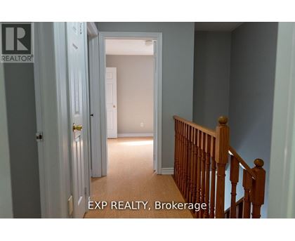 A hallway with a wooden staircase and a door on the left.