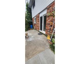 A small backyard with a concrete patio and a brick wall.