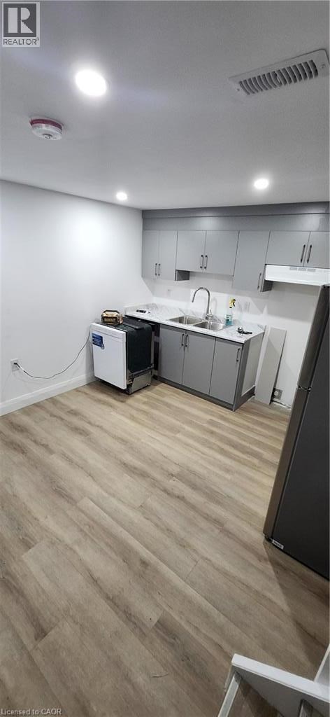 A kitchen with a refrigerator, sink, and cabinets.