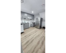 A kitchen with wooden flooring and stainless steel appliances.