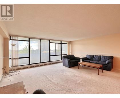 A living room with a couch, chair, and large windows.