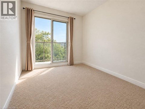 A room with a carpeted floor and a large window with curtains.