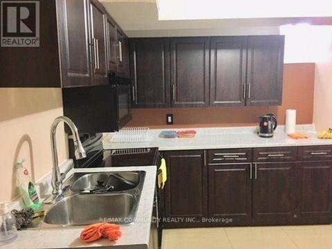 A kitchen with dark brown cabinets and a sink.