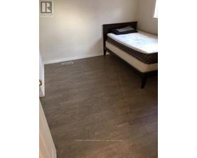 A bedroom with a bed and a wooden floor.