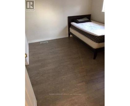 A bedroom with a bed and a wooden floor.