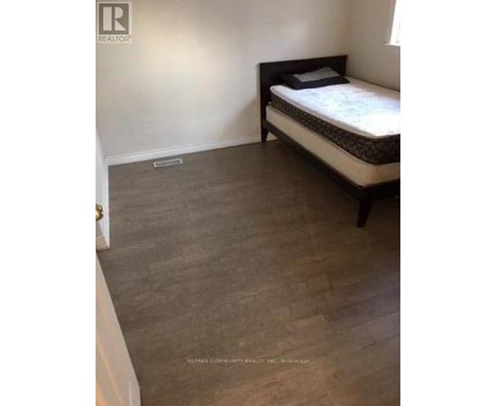A bedroom with a bed and a wooden floor.
