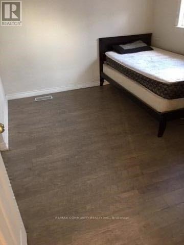 A bedroom with a bed and a wooden floor.