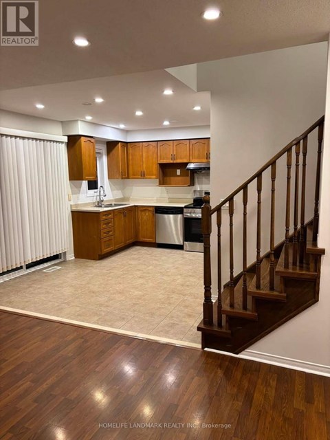 A well-lit kitchen with wooden floors and a staircase.