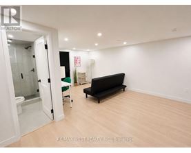 A room with a black couch and a glass door leading to a bathroom.
