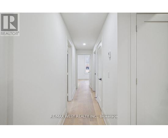 A long white hallway with a door on the right.