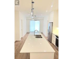 A modern kitchen with a white countertop and stainless steel appliances.