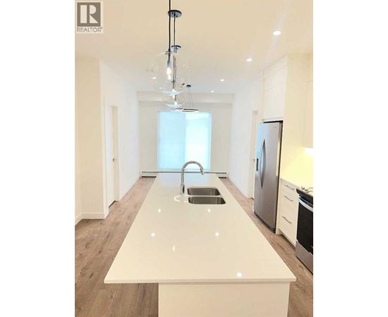 A modern kitchen with a white countertop and stainless steel appliances.