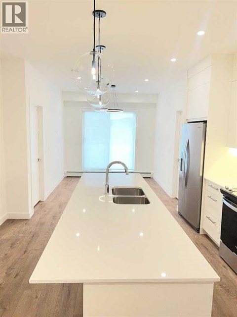 A modern kitchen with a white countertop and stainless steel appliances.