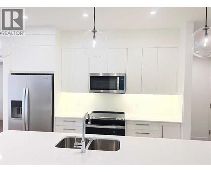 A modern kitchen with white cabinets and stainless steel appliances.