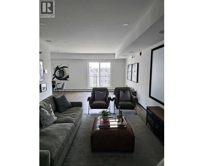 A living room with a grey couch, a brown coffee table, and a large window.
